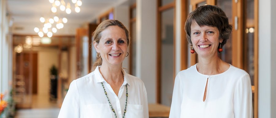 Två medarbetare på Borgerskapets vård- och omsorgsboende som ler i en ljus korridor.