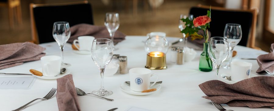 En elegant dukning med vit duk, porslinstallrikar, glas och en blomsterdekoration på vård- och omsorgsboendet.